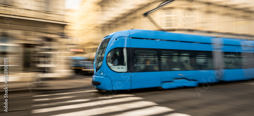 blue modern tram moving fast through city street representing urban transportation system