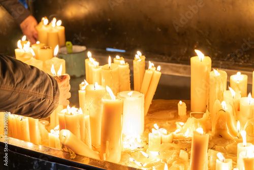 person lighting and arranging multiple candles indoors creating a warm peaceful ambiance