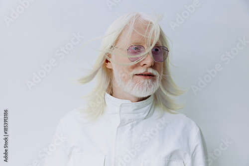 Obraz na plátne Elderly man with white hair and glasses, wearing a white shirt, set against a so