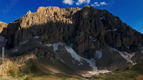 A mountain with snow on it and a clear blue sky. The mountain is very tall and rocky