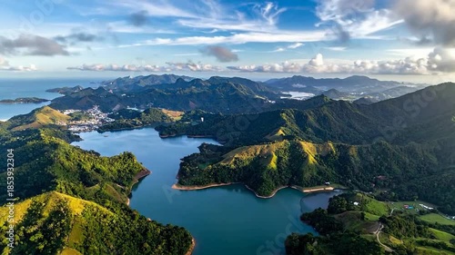 Aerial View of Lush Green Mountains and Blue Lake Under a Cloudy Sky