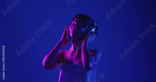 Wallpaper Mural A woman wearing headphones, immersed in music, is illuminated by vibrant purple and blue neon lights. Slow motion. Torontodigital.ca