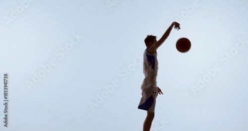 Basketball athlete raising ball high while jumping forward in expressive slam dunk motion. Concept of confident stance, guided movement, directional signaling, and active play communication.