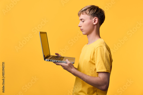 Принти на полотні Youth with laptop in a yellow studio, showcasing technology, learning, and onlin