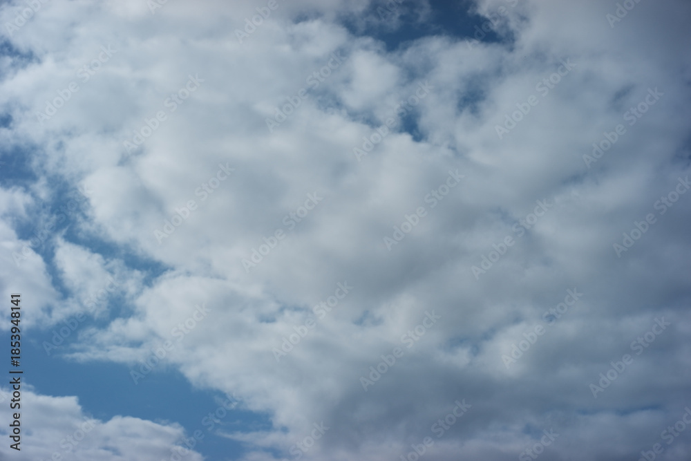 Obraz premium Serene and peaceful blue sky filled with fluffy white cloud. beautiful nature background of daytime weather, offering sense of calm and vastness, perfect backdrop