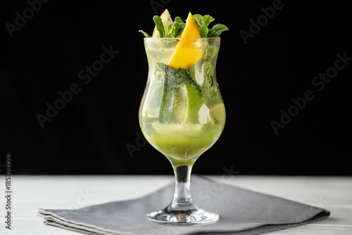 Mint lemon cocktail with lime in tall glass on black background