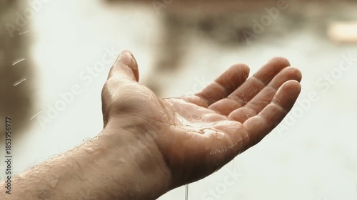 Rain falling on an open male hand, metaphor of change and seasons
