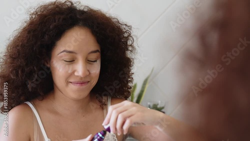 A young Latina woman carefully applies mascara while looking in the bathroom mirror. Intimate beauty routine highlighting precision, self-care, and daily preparation.