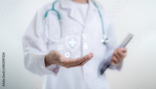 Doctor presents digital healthcare protection concept with medical shield icons above open hand while using tablet representing telemedicine data security insurance and modern medical technology
