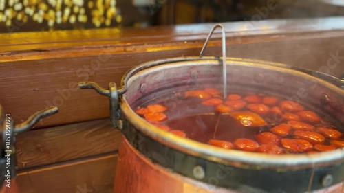 A large metal pot filled with hot mulled drink and floating orange slices at a festive outdoor market.