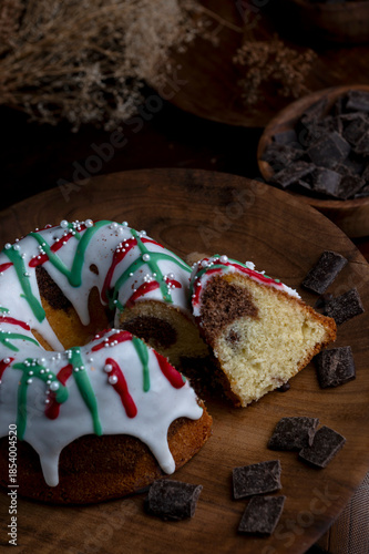 Vanilla and chocolate pudding covered with white sugar sauce, decorated with red and green icing and coffee beans in a kitchen with wood 
