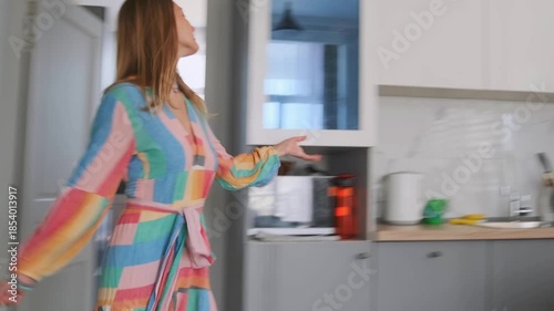 woman enjoys lively morning dance, woman in cheerful dress dances joyfully in sunlit kitchen during morning hours, woman dressed colorfully delights in dancing happily within her sunny kitchen