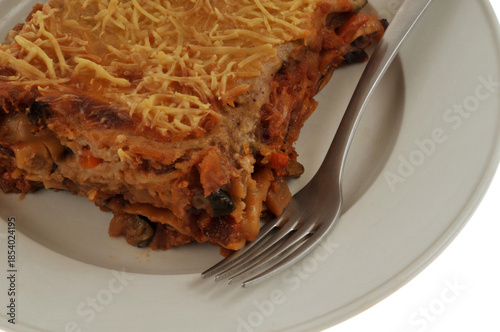 Part de lasagnes aux légumes maison servie dans une assiette avec une fourchette en gros plan