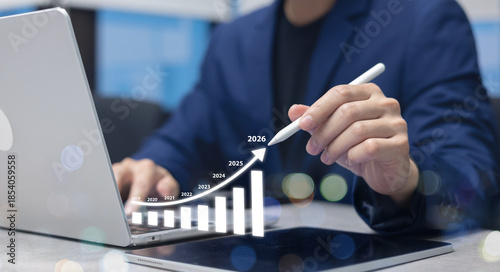 close up businessman hand use stylus pen to write virtual statistic graph about business plan and target of company over black background for future and 2026 new year goal concept