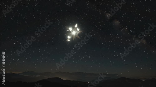 Bright cross-shaped flare hovering above a quiet desert horizon under a starry night sky