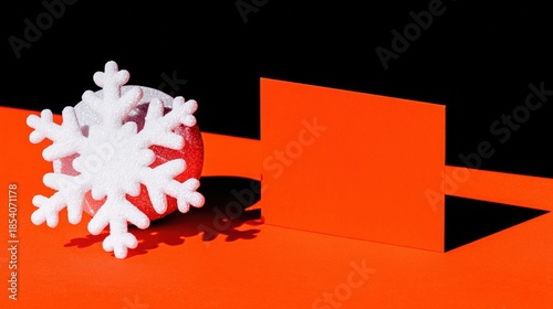 Christmas festive decor: white foam snowflake on red glossy bauble, placed on bold orange geometric paper background with black backdrop and sharp shadow. Ideal for wallpaper, poster