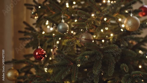 Close-up view of a softly lit Christmas tree adorned with baubles and twinkling lights