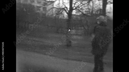 Two cheerful friends in winter clothing walking along autumn city street. Young men smiling, laughing, talking together despite gray weather in urban outdoor. Old film. Archival retro. Vintage archive