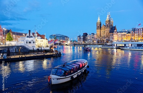 Photography A tour boat cruising on the canal near Amsterdam's Central Railway Station, with