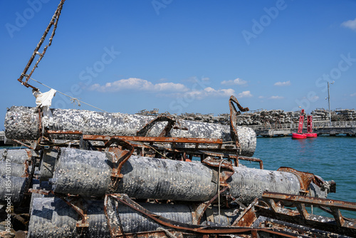 Rusty, barnacle-covered metal pipes at an abandoned harbor symbolize the environmental impact of industry on marine ecosystems.