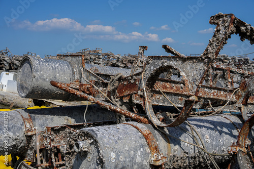 Rusty, barnacle-covered metal pipes at an abandoned harbor symbolize the environmental impact of industry on marine ecosystems.