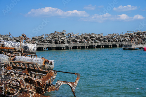 Rusty, barnacle-covered metal pipes at an abandoned harbor symbolize the environmental impact of industry on marine ecosystems.