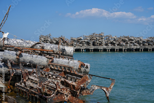 Rusty, barnacle-covered metal pipes at an abandoned harbor symbolize the environmental impact of industry on marine ecosystems