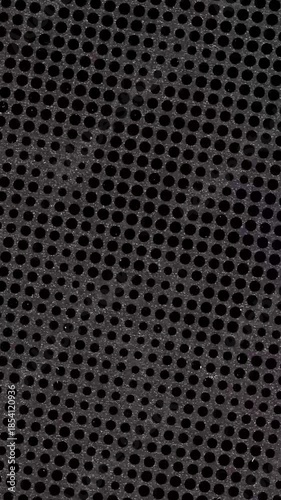 Black metal surface with small round holes forms a pattern