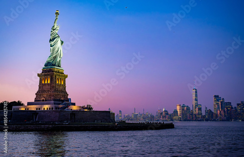 Statue of Liberty at twilight with Manhattan skyline. The Statue of Liberty at twilight with the Manhattan skyline glowing in the distance.