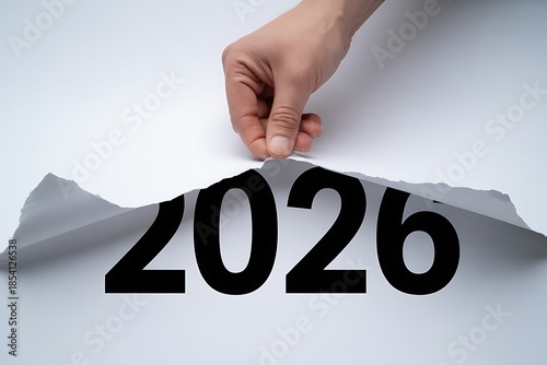 A hand pulling back a torn piece of paper revealing the year 2026 underneath