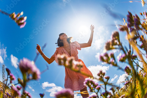 Summer mood. young and cheerful girl in summer dress posing against blue sky and flowers. beautiful girl dancing among flowers. girl enjoying summer.