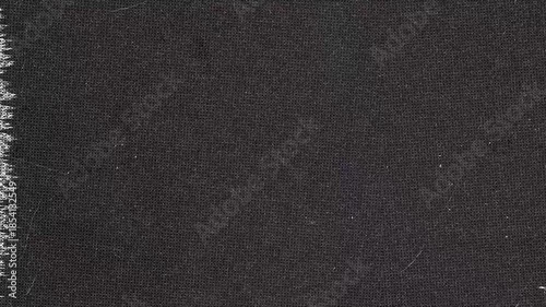 Dark woven fabric material with frayed edges and some minor imperfections