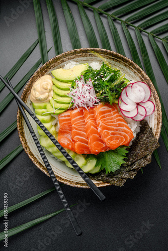 Salmon Poke Bowl with Sliced Radish and Creamy Sauce. This visually appealing salmon poke bowl is neatly arranged with sliced salmon, avocado, radish, and seaweed, featuring a creamy sauce.