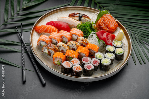 Variety Platter of Sushi, Sashimi, and Maki Rolls. A circular plate features a rich variety of nigiri, sashimi, and maki rolls, showcasing tuna, salmon, eel, and vegetable fillings.