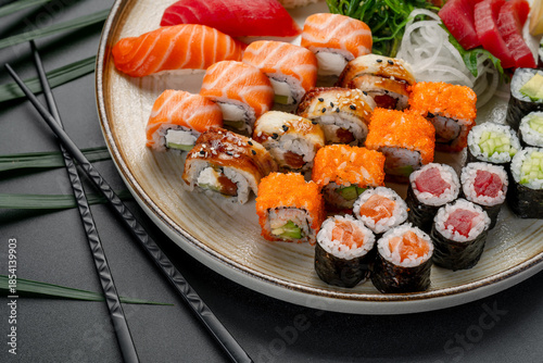 Variety Platter of Sushi and Maki Rolls on Plate. A large platter features a diverse assortment of fresh nigiri, sashimi, and maki rolls arranged elegantly on a textured plate.