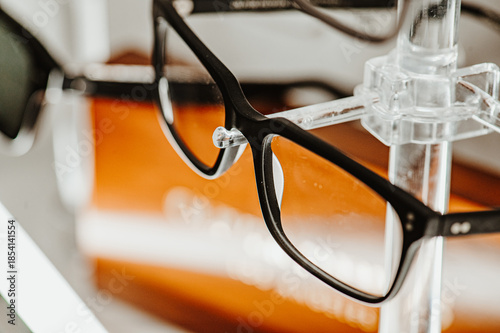 Black eyeglass frames in retail stand. Optical product assortment located on transparent holder
