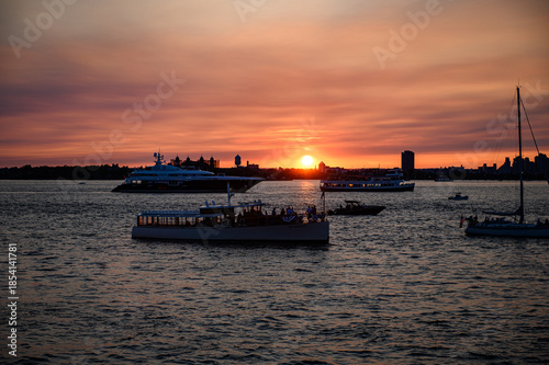 New York, USA, 9 December 2025: Deep red sunset on Hudson. A deep red sunset lights boats and buildings along the Hudson River.