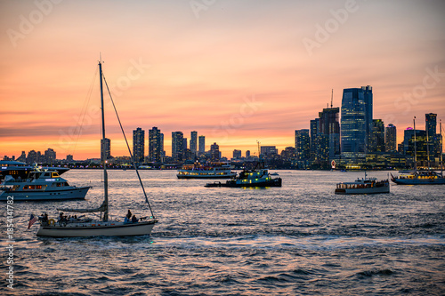New York, USA, 9 December 2025: Boats and skyline at twilight. Hudson River boats pass a glowing Manhattan skyline at twilight.