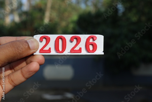 New year 2026 is been 3d printed on a small piece of PLA material and held in the hand on a natural background