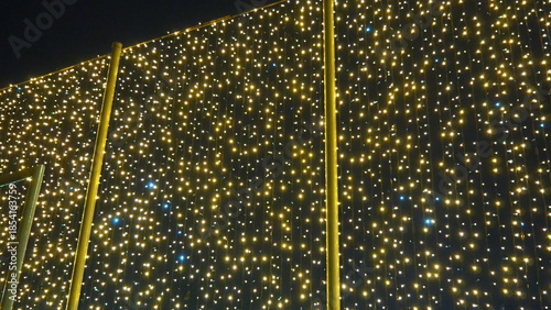 Flashing yellow and blue modern garlands of light bulbs in evening darkness. Theme of the New Year and Christmas. A background of sparkling light bulbs. Festive mood. Window and street decoration