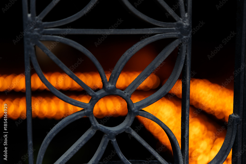 Naklejka premium Warm temple oil lamps glowing behind decorative iron grille.