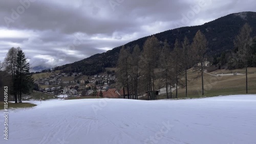 Spring Thaw in Mountains with Green Grass Appearing Through Melting Snow, Climate Change and Global Warming Concept, End of Winter Season in Ski Resort