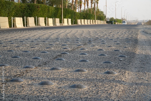 Speed bump on asphalt road closeup, Metal road studs for traffic calming device for slowing down according to speed limit. City of El Quseir on the Red Sea, Northern Egypt, Africa.