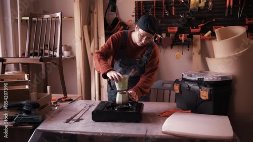 Female artisan brewing fresh coffee with moka pot during work break in carpentry workshop