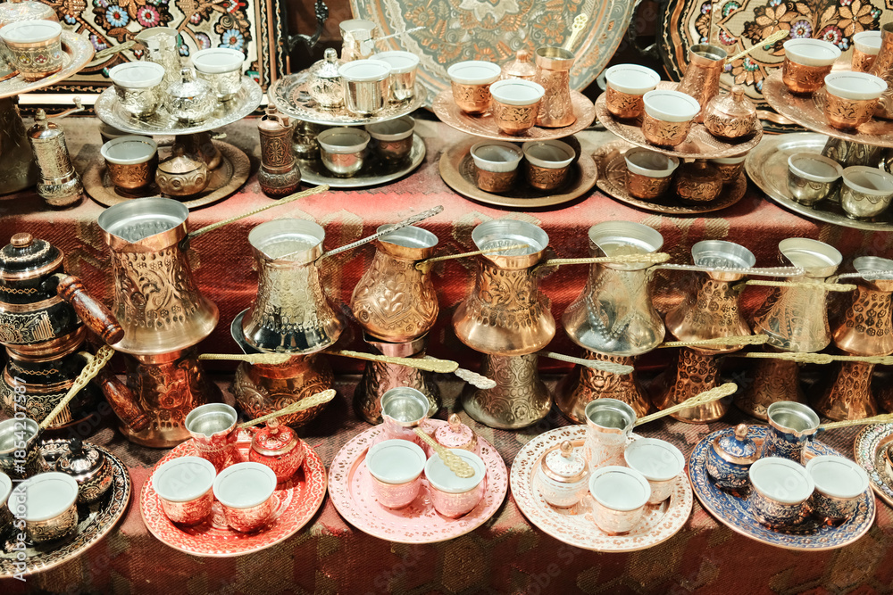 Fototapeta premium Traditional copper coffee pots and cups arranged for sale at a local market in Bosnia and Herzegovina. Authentic Balkan tableware and cultural souvenirs.