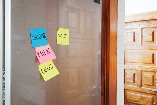 Refrigerator door with colorful handwritten shopping list sticky notes