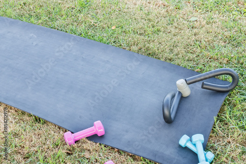 Exercise mat with dumbbells and leg toner on grass