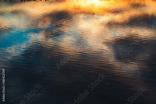 bellissimo riflesso del cielo azzurro ed arancione e nuvoloso, al tramonto, su uno specchio d'acqua tranquillo
