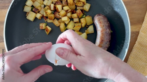 Cooking Fried Eggs in a Pan with Sausages and Fried Hash Brown Potatoes