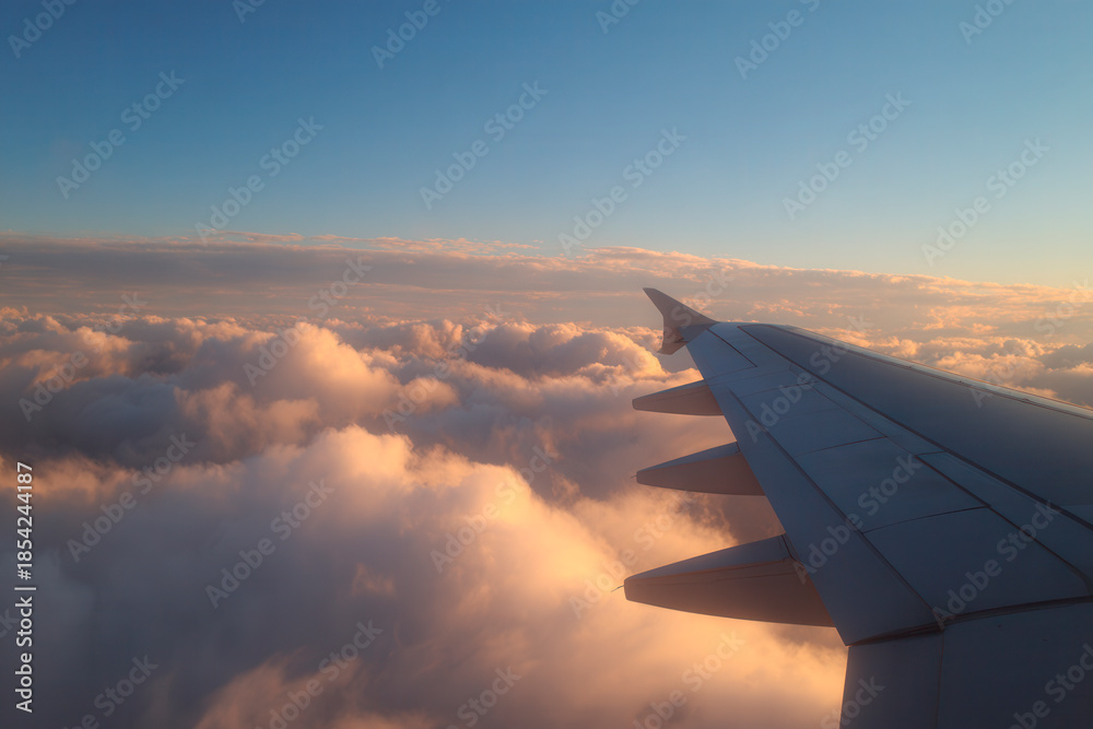 Obraz premium Airplane wing above clouds in golden light
